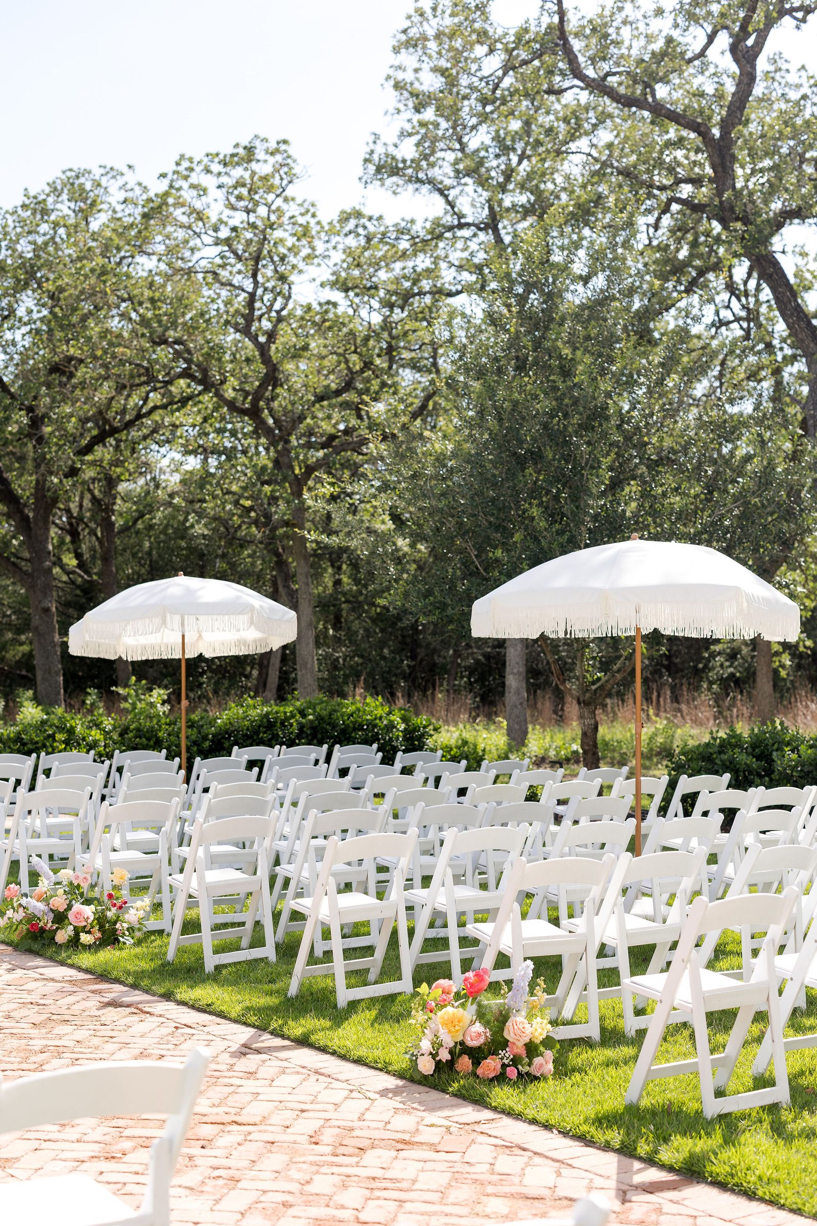 Ceremony setup with white chairs and market umbrellas